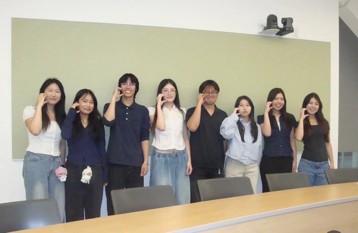 Emily and her #Include teammates standing together in front of a classroom chalkboard after presenting the JCC project.